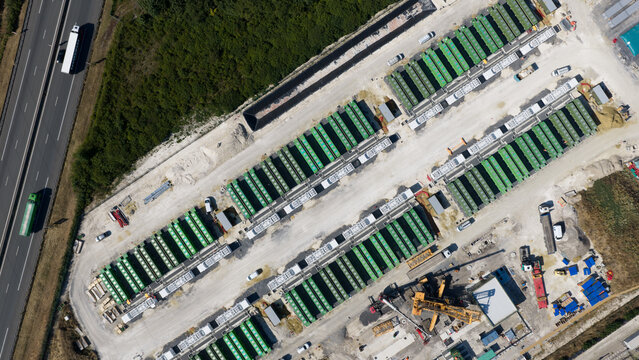 Saleux, France - 08 July 2026: Aerial view of rows of green industrial containers arranged in a construction site next to a highway with heavy machinery and vehicles visible.
