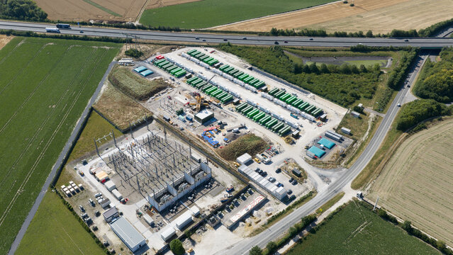 Saleux, Hauts-de-France, France - 08 July 2026: Aerial view of a power substation and battery energy storage facility with rows of green containers near a highway and farmland.