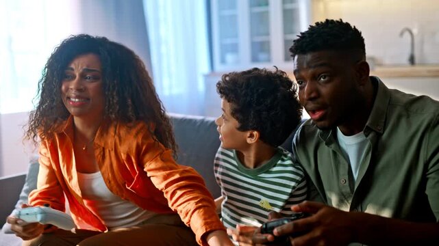 Multiethnic family playing video game living room. Mother son dad upset losing.