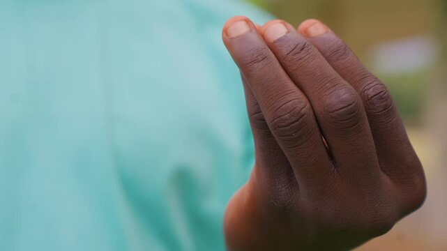 Close up focus on detailed lines and contours of adult human hand in motion against soft blue background. visible skin texture including wrinkles around knuckles and fingers suggests natural
