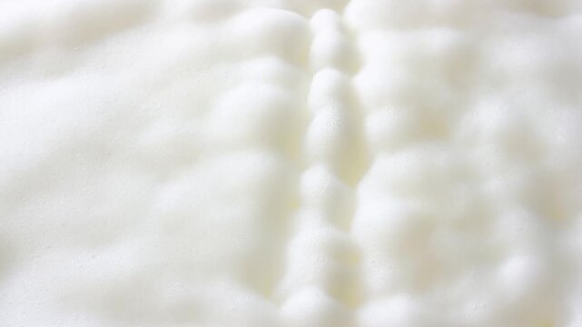 White foamy surface forms soft rounded mounds with faint yellow patches in closeup