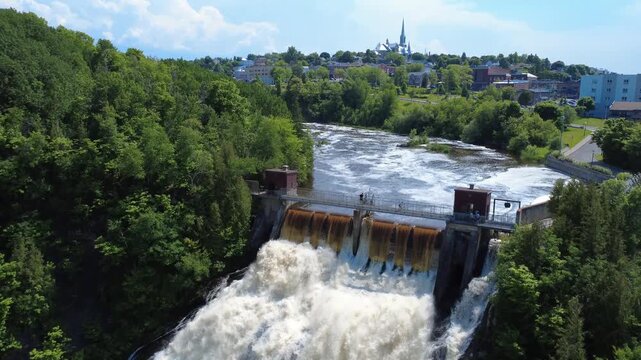 Aerial drone footage of Parc de la Petite Chute in Rivi&egrave;re-du-Loup, showing several tourists on a footbridge above a natural waterfall in Quebec, Canada.