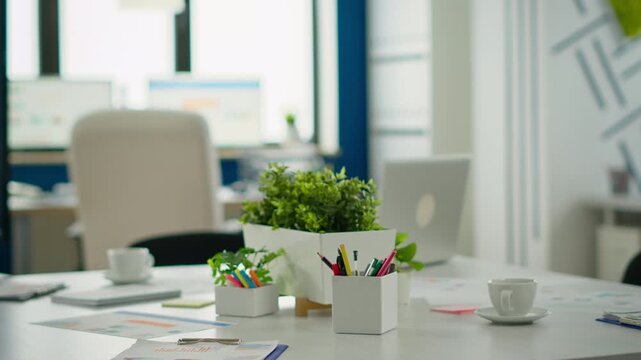 Office, empty workspace and planning center on a conference table with plants, reports and colorful stationery in a bright modern interior, ready for meetings, organization, productivity and teamwork.