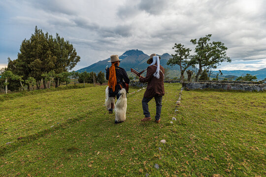Scenic Andean mountain landscape with traditional stone circle site and indigenous musicians