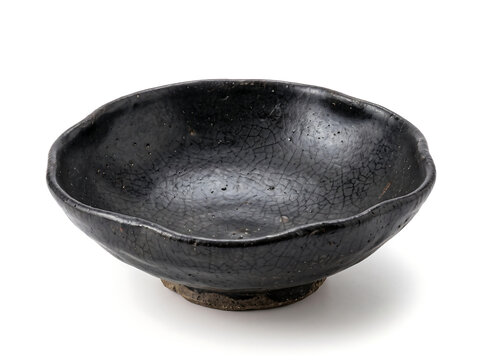 Handmade black ceramic bowl with crackle glaze and rustic unglazed foot on white background