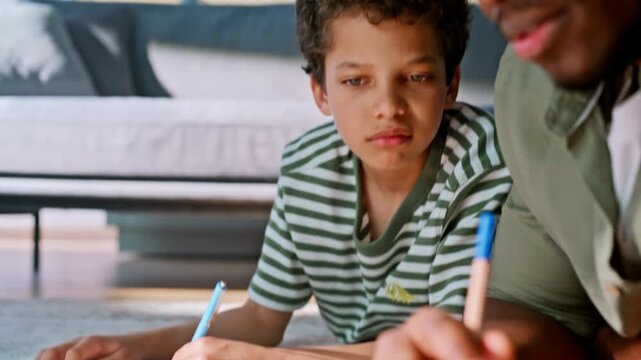 Boy writing workbook, father explaining lesson. Close up family homework home.