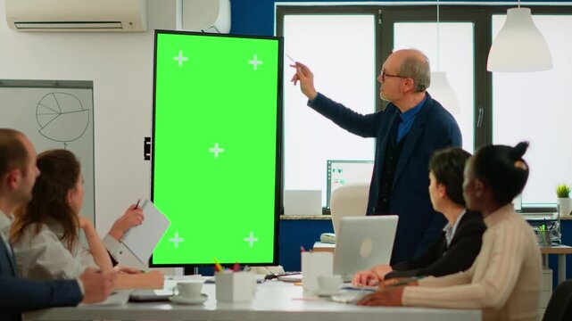 Greenscreen, leadership and businessman gesturing beside a vertical chroma key display during office meeting, for professional briefing, project strategy, teamwork, communication and custom media.