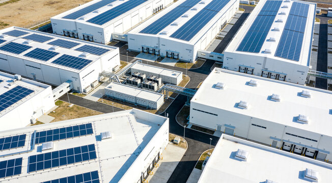 An aerial view of a massive industrial park complex featuring several large warehouses with solar panels.