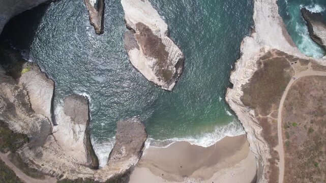 Aerial top-down over turquoise water and white sea stacks, revealing Shark Fin Cove