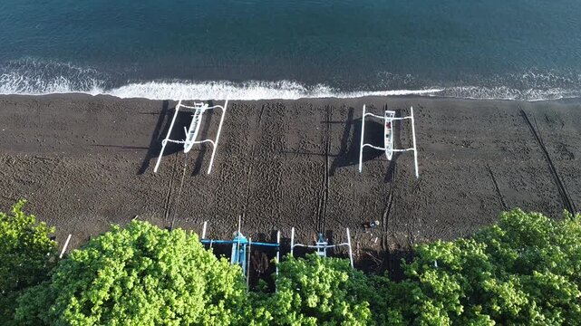 Fishermen return in the morning with their outrigger boats to the black beach of Amed, with Mount Agung in the background, Amed Bali, Indonesia