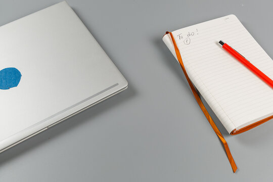Workspace with laptop, notebook, and pen on a gray desk for planning tasks