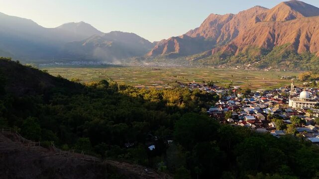 Aerial view of Bukit Selong overlooking the village of Sembalun with its mosque and surrounding agricultural fields nestled in the mountains of Sembalun, West Nusa Tenggara, Indonesia.