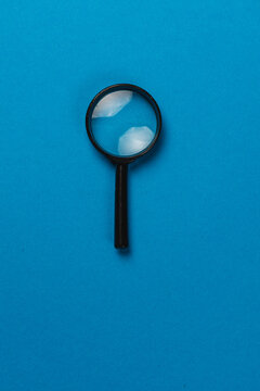 Magnifying glass on blue background for searches and investigations