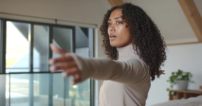 African American woman extending right arm near glass doors in loft toward camera