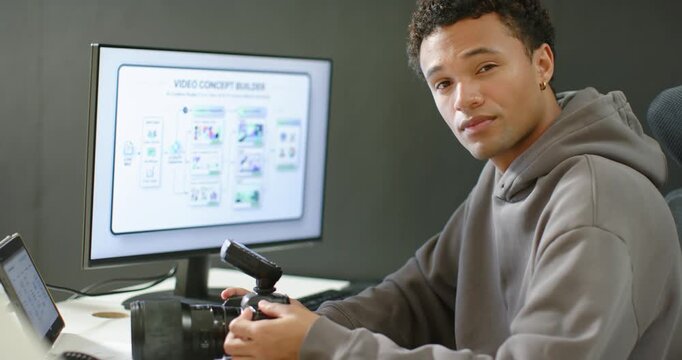 African American man adjusting DSLR at desk noticing recorder and prepping Concept Builder, smiling