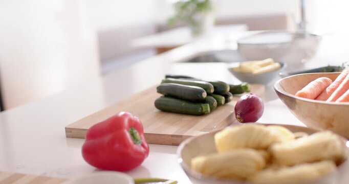 Camera is dollying forward and focus is shifting, highlighting zucchinis on cutting board for prep