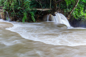 Kuang Si Waterfall cascades over tiered rocky ledges into a wide river in a lush tropical forest near Luang Prabang, Laos. © Eugene Ga