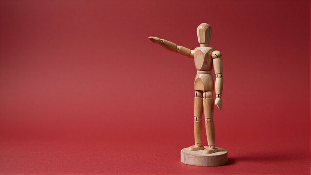 Wooden mannequin gestures forward against a solid red background.