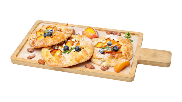 Delicious homemade fruit galettes with baked peaches and fresh blueberries served on a wooden board isolated on white background