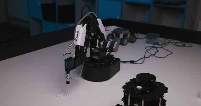 Robotic arm lowers its gripper toward a paper sheet on a laboratory table during a precision automation demonstration