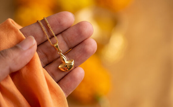 Gold diya pendant necklace held in hand representing traditional Indian festival celebration jewelry
