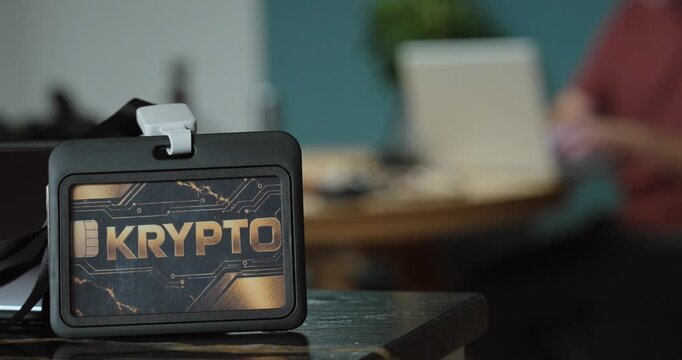 Close-up of a crypto payment card in the foreground with a man using a laptop in the background. Concept for cryptocurrency, online banking, blockchain and digital finance.