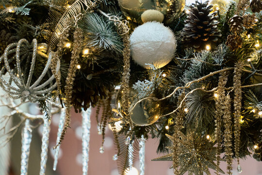 White Christmas Ornament Hangs Among Pinecones and Fairy Lights