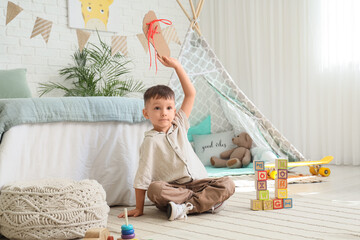 Early childhood development and learning, boy practicing lacing skills with cardboard shoe in nursery room for preschool education and motor skills © Pixel-Shot