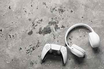 Gaming and entertainment lifestyle, white wireless game controller and headphones on a textured gray concrete background with copy space for text © Pixel-Shot