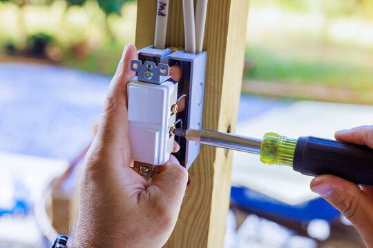 Electrician installing an outlet box on wooden frame at an outdoor work site