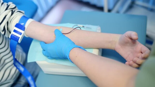 A nurse takes blood from a child using butterfly needle. Close up video of a boy's hand while taking a blood sample for examination in a modern laboratory or hospital. Baby health check