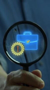 Hand holding magnifying glass vertical shot inspecting business briefcase and gear with exclamation mark icon. Corporate financial audit risk inspection, operational alert, and compliance concept.