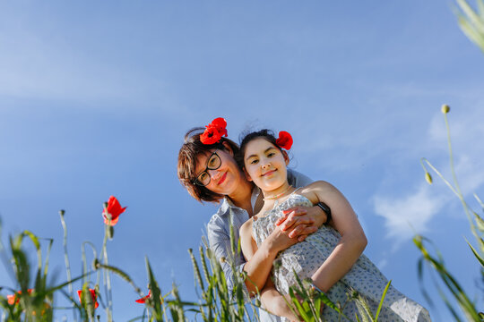 Mother and daughter embracing with red poppies in their hair