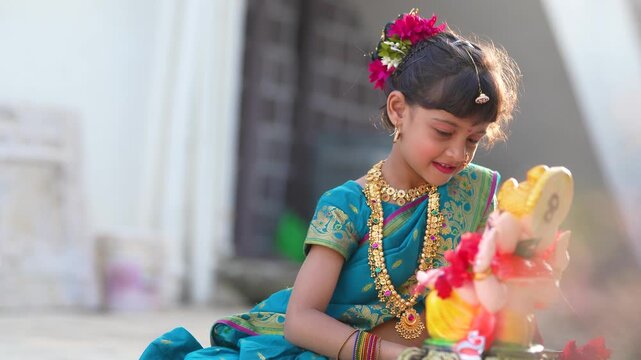 indian little girl doing puja of lord Ganesha sculpture at out of home