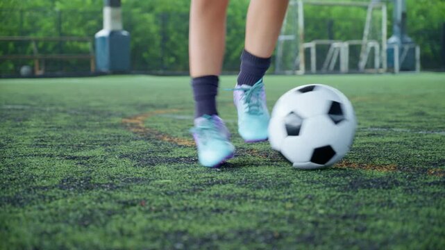 Close-up of a boy kicking a soccer ball on a green turf field, with sharp detail and frozen motion, representing youth sports, training, fitness and a healthy active lifestyle.