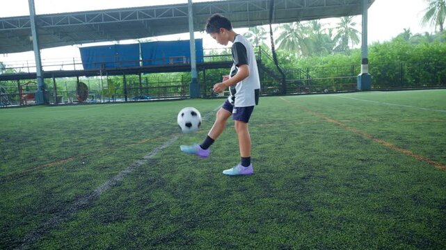 Close-up of a boy kicking a soccer ball on a green turf field, with sharp detail and frozen motion, representing youth sports, training, fitness and a healthy active lifestyle.