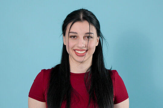Portrait of a smiling young woman with long black hair on blue background