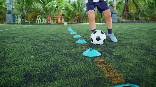 Close-up of a boy kicking a soccer ball on a green turf field, with sharp detail and frozen motion, representing youth sports, training, fitness and a healthy active lifestyle.