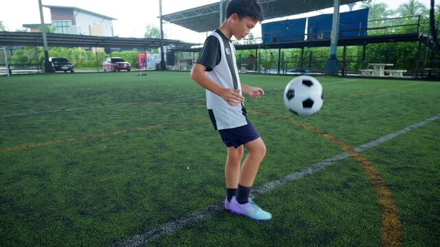 Close-up of a boy kicking a soccer ball on a green turf field, with sharp detail and frozen motion, representing youth sports, training, fitness and a healthy active lifestyle.