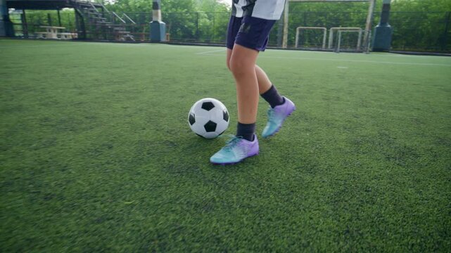 Close-up of a boy kicking a soccer ball on a green turf field, with sharp detail and frozen motion, representing youth sports, training, fitness and a healthy active lifestyle.