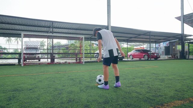 Close-up of a boy kicking a soccer ball on a green turf field, with sharp detail and frozen motion, representing youth sports, training, fitness and a healthy active lifestyle.