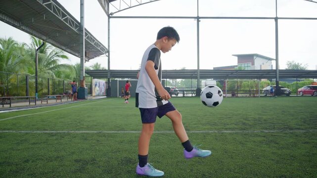 Close-up of a boy kicking a soccer ball on a green turf field, with sharp detail and frozen motion, representing youth sports, training, fitness and a healthy active lifestyle.