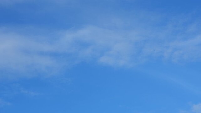 A blue sky timelapse featuring delicate cirrostratus and wispy cirrus clouds spreading into translucent layers, creating subtle atmospheric textures as sunlight filters through thin cloud veils. 4k.
