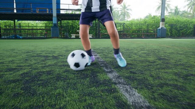 Close-up of a boy kicking a soccer ball on a green turf field, with sharp detail and frozen motion, representing youth sports, training, fitness and a healthy active lifestyle.