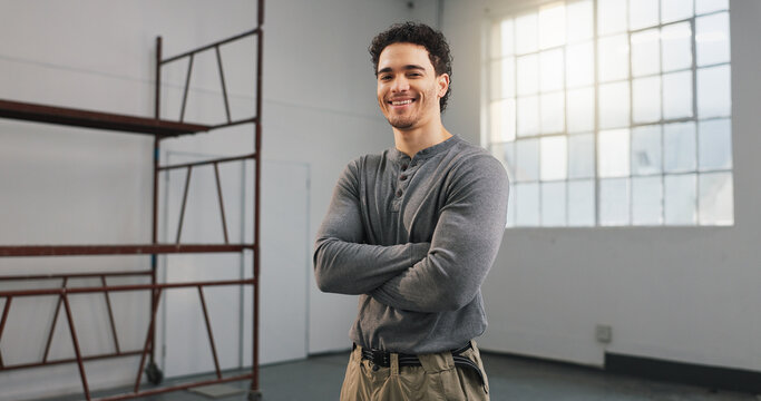 Building, renovation and employee with smile at construction site, engineering and arms crossed. Man, laborer and confidence in portrait, pride and happy with property expansion or remodeling