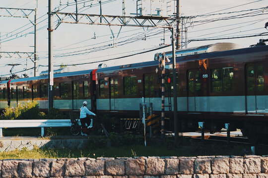 踏切で電車を待つ自転車利用者の日常風景