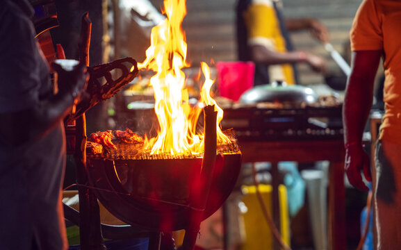 Street food barbecue grill with flames and vendors cooking at night
