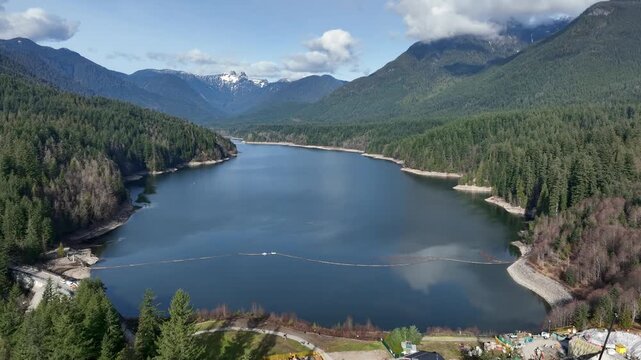 Capilano Lake Surrounded By Dense Evergreen Forest And Mountains In North Vancouver, British Columbia, Canada. - aerial shot