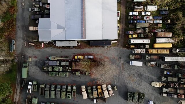 Junkyard Filled With Abandoned Trucks And Vehicles Parked Among Scrap Materials, Outdoor Vehicle Storage And Salvage Area. Aerial Shot