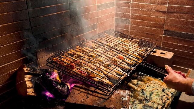 Butterflied Portuguese king prawn with a garlic basting sauce in a grill and cooking over flames and wooden coals